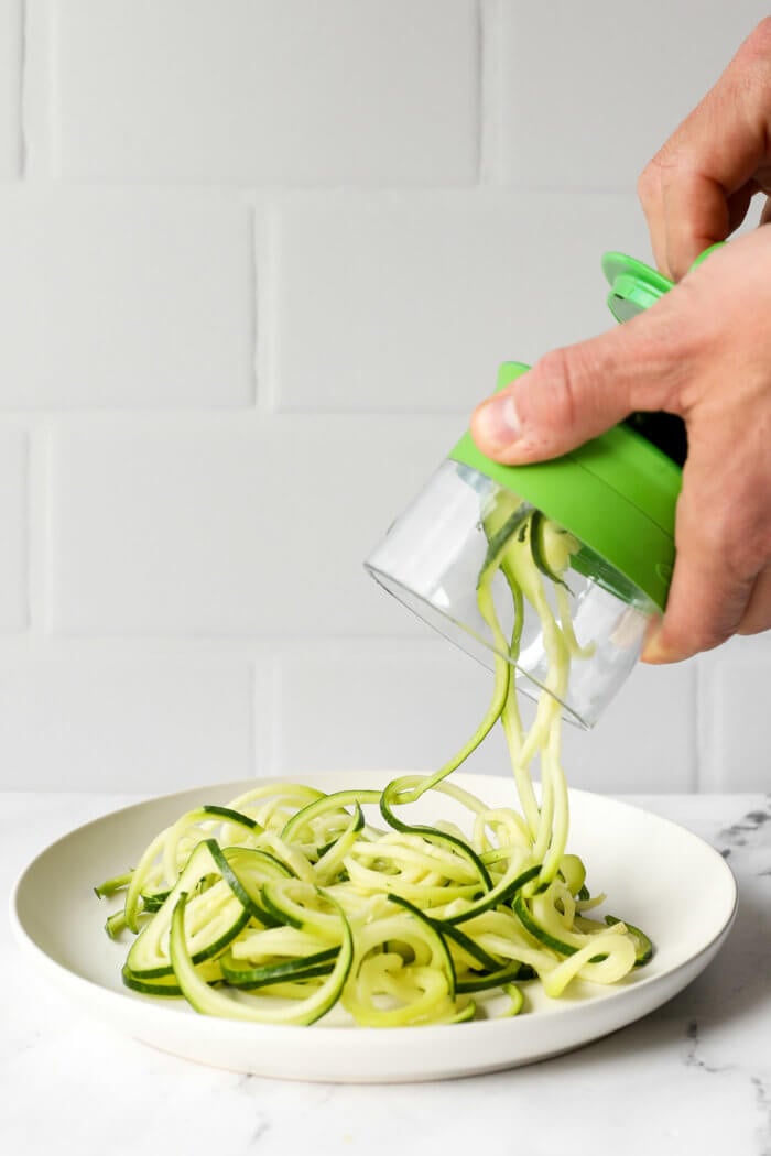 Image of making zucchini noodles with a handheld spiralizer.