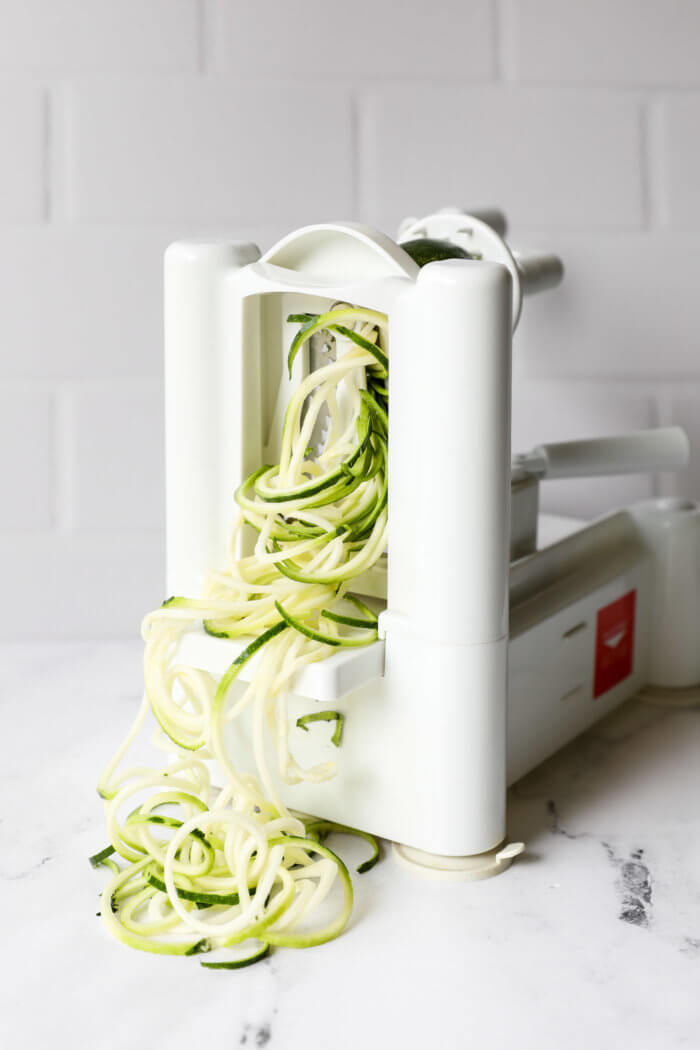 Image of zoodles coming out of a stand up spiralizer.