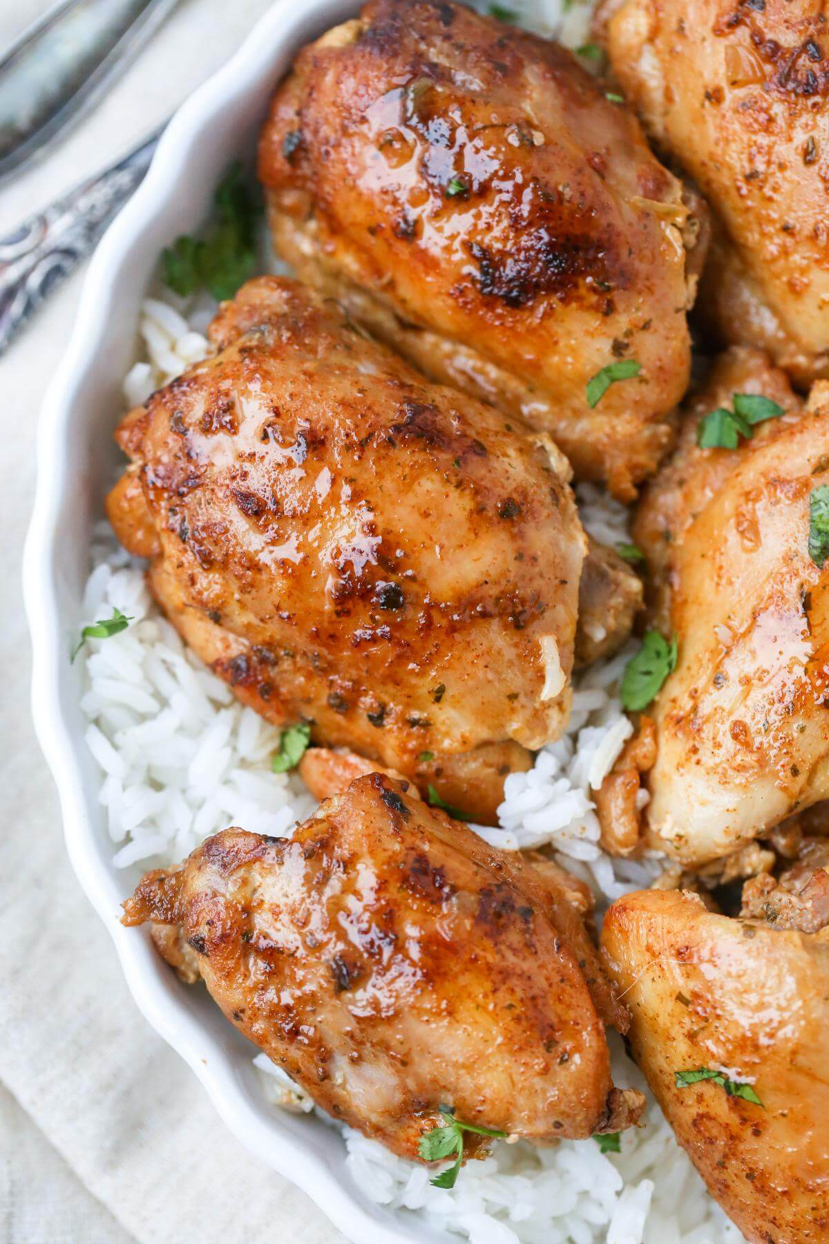 Skin on chicken thighs with sauce over rice in a bowl