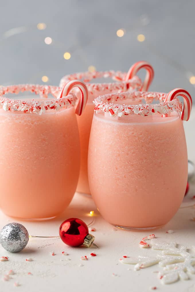 2 peppermint pina coladas with crushed peppermint candy cane rims and candy canes sticking out